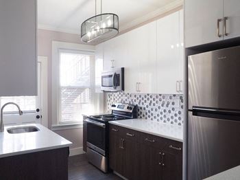 A modern kitchen with dark wood cabinets and stainless steel appliances at The Packard, West Hartford, 06119